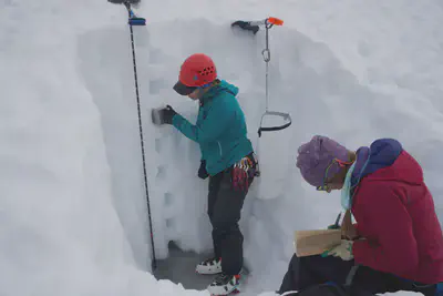 Gemma O'Connor measuring snow densities and Erin Whorton taking notes.